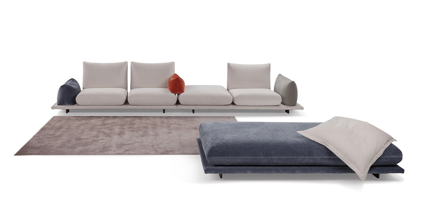 Modular 'Pralin' sofa with removable elements, wooden feet, and versatile configurations, including a day bed and integrated table, ensures customizable comfort and relaxation. | Pralin by Calia Italia