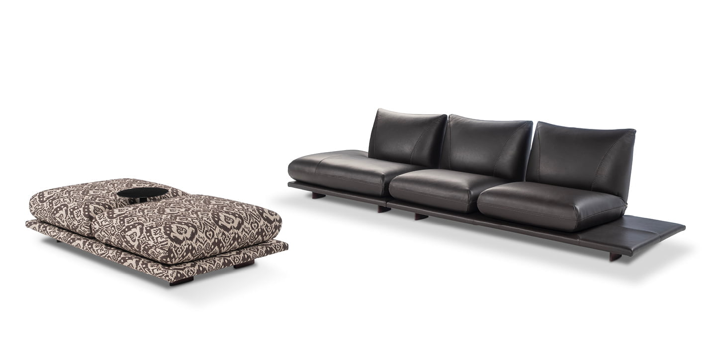 Modular 'Pralin' sofa with removable elements, wooden feet, and versatile configurations, including a day bed and integrated table, ensures customizable comfort and relaxation. | Pralin by Calia Italia